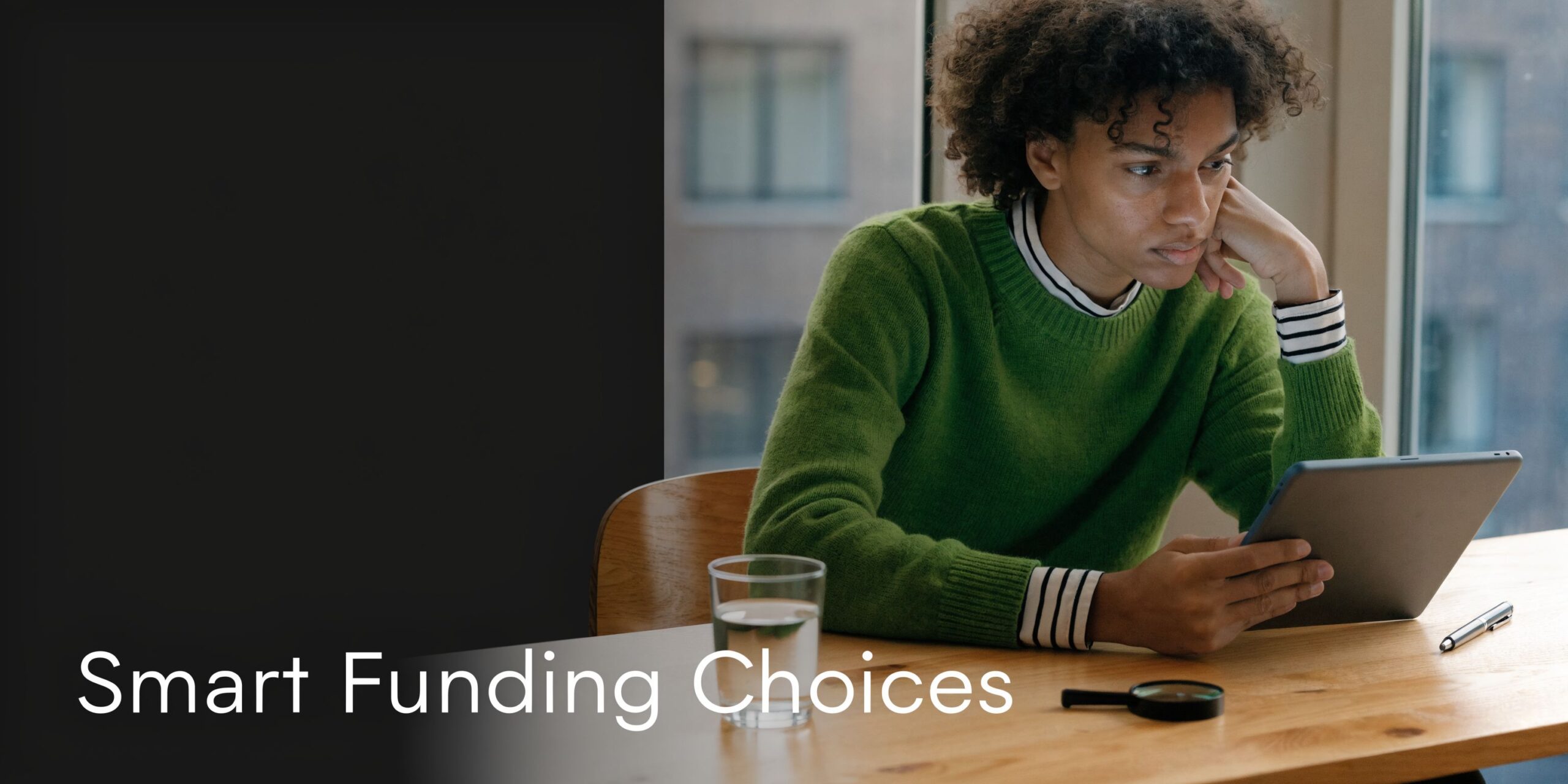 A young person with curly hair sits at a wooden desk using a tablet to plan home improvements.